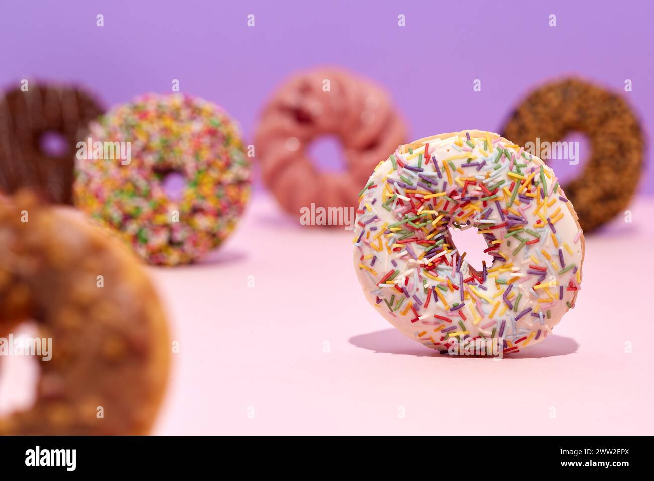 Un gruppo di ciambelle con spruzzette su sfondo rosa Foto Stock