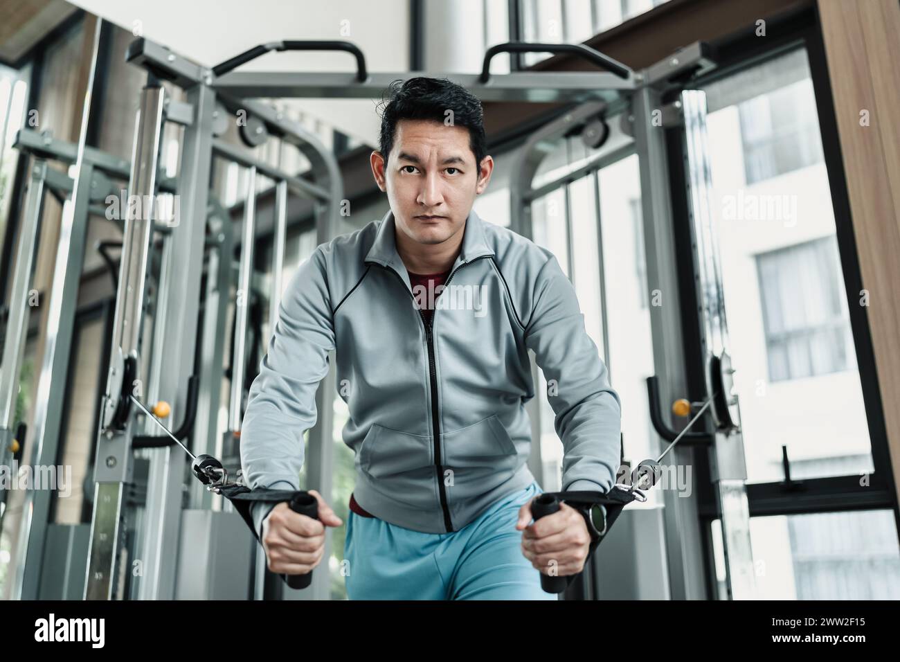 Un uomo che lavora sul suo torace con Cable Crossover in palestra. Concetto di fitness, allenamento, sport e salute. Foto Stock