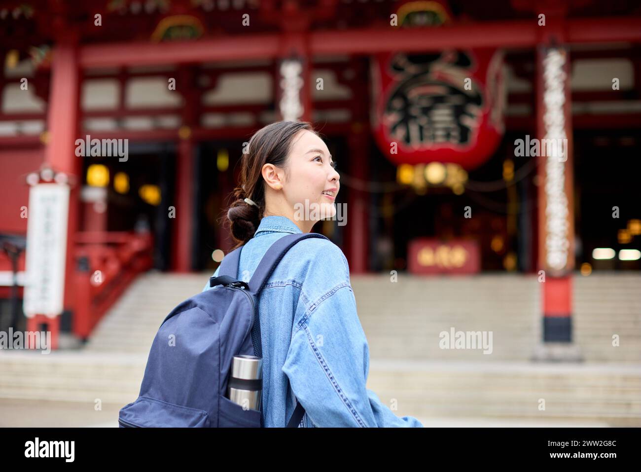 Una donna con uno zaino che cammina davanti a un tempio Foto Stock