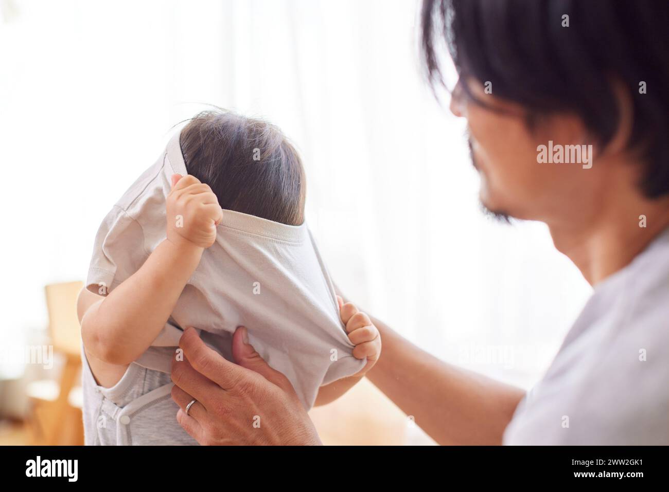 Papà asiatico che aiuta il bambino a vestirsi Foto Stock