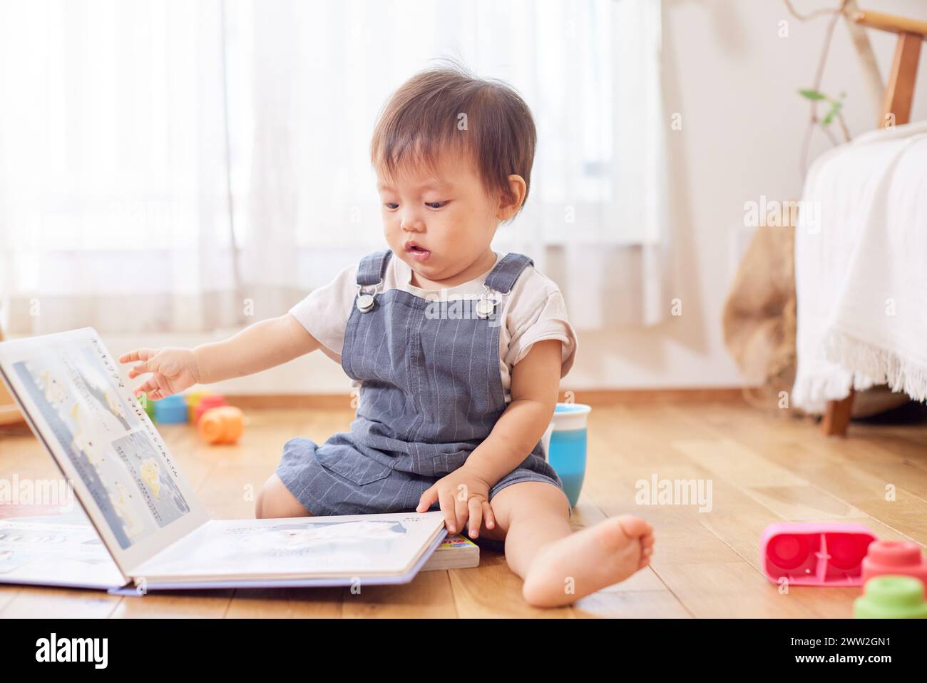 Un baby sitter sul pavimento che gioca con un libro Foto Stock