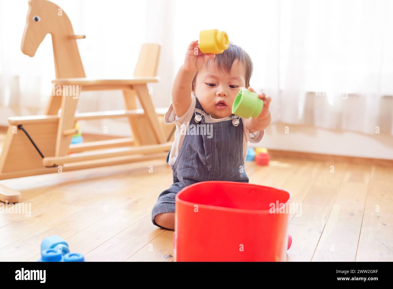 Un bambino che gioca con i giocattoli sul pavimento Foto Stock