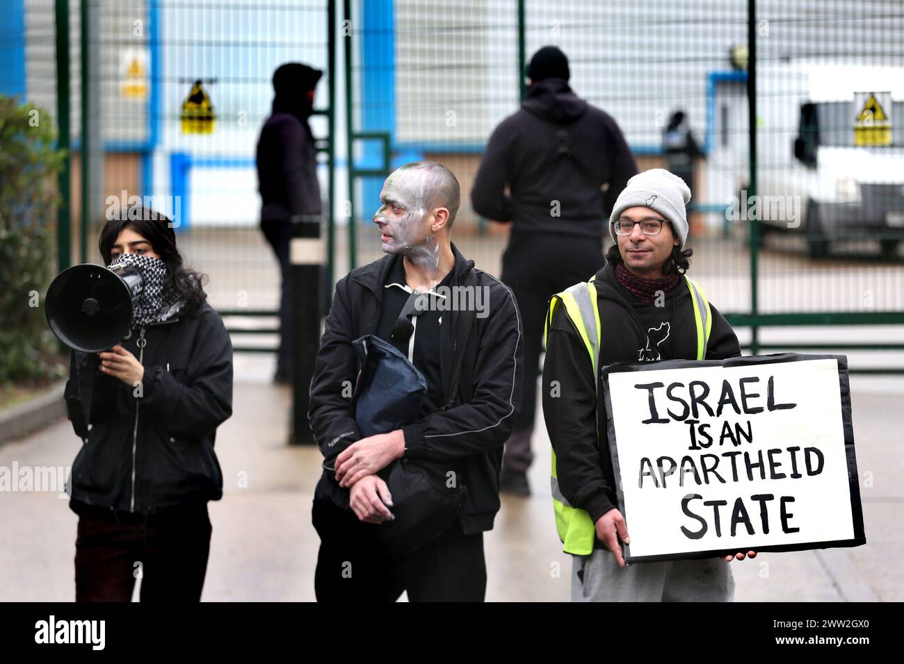 I manifestanti cantano e tengono un cartello che dice "Israele è uno Stato apartheide" fuori dalla fabbrica durante la dimostrazione. I manifestanti si riuniscono fuori dalle porte della fabbrica della Elbit System a Leicester per confrontarsi con i lavoratori che arrivano per lavoro con cartelli e canti che fanno sapere loro cosa pensano della compagnia israeliana di armamenti e del loro ruolo nell'oppressione dei palestinesi a Gaza e altrove. Il 20 marzo ha visto l'azione nazionale al di fuori delle fabbriche di armi complice come i manifestanti lo vedono nel genocidio israeliano a Gaza. (Foto di Martin Pope/SOPA Images/Sipa USA) Foto Stock