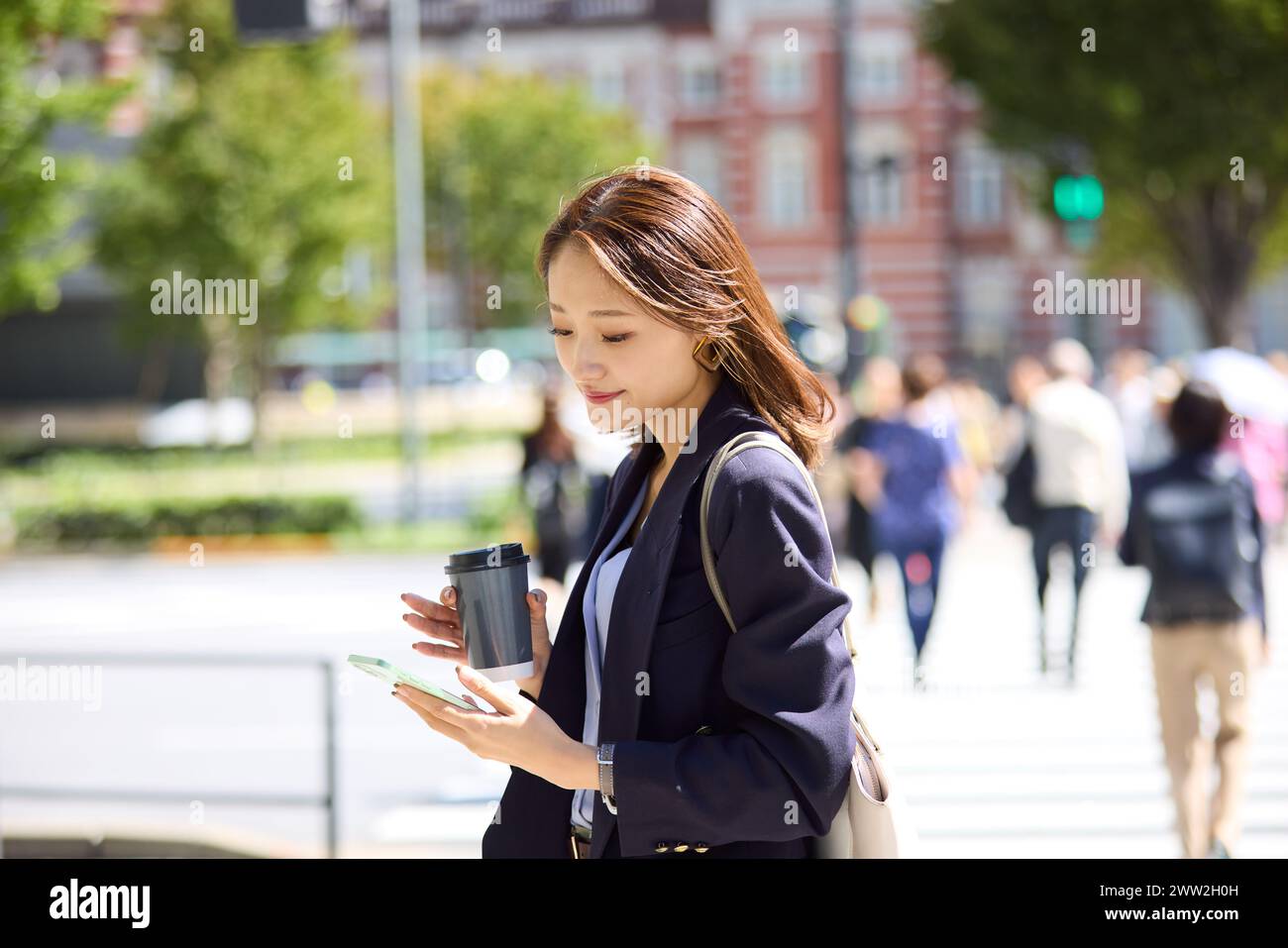 Donna asiatica che usa lo smartphone mentre cammina per strada Foto Stock