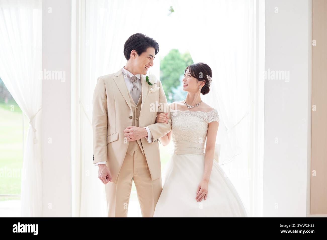 Una sposa e uno sposo in piedi davanti a una finestra Foto Stock