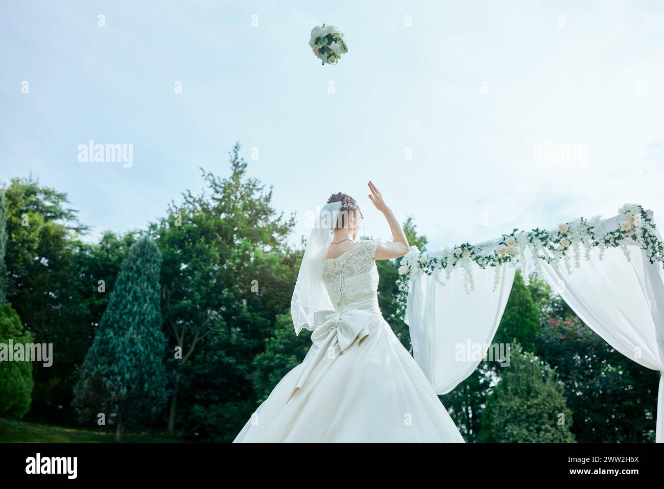 Una sposa lancia il suo bouquet in aria Foto Stock