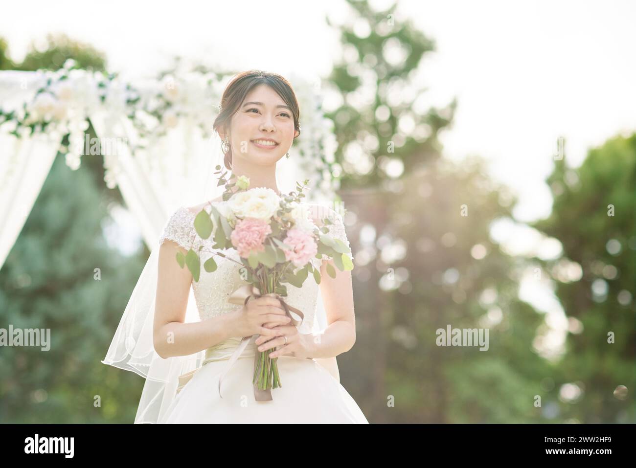 Una donna con un abito da sposa in possesso di un bouquet Foto Stock