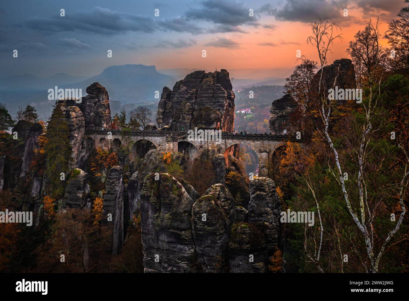 Sassonia, Germania - il ponte Bastei con un tramonto autunnale soleggiato con fogliame colorato e cielo. Bastei è famosa per la splendida formazione rocciosa di Saxo Foto Stock