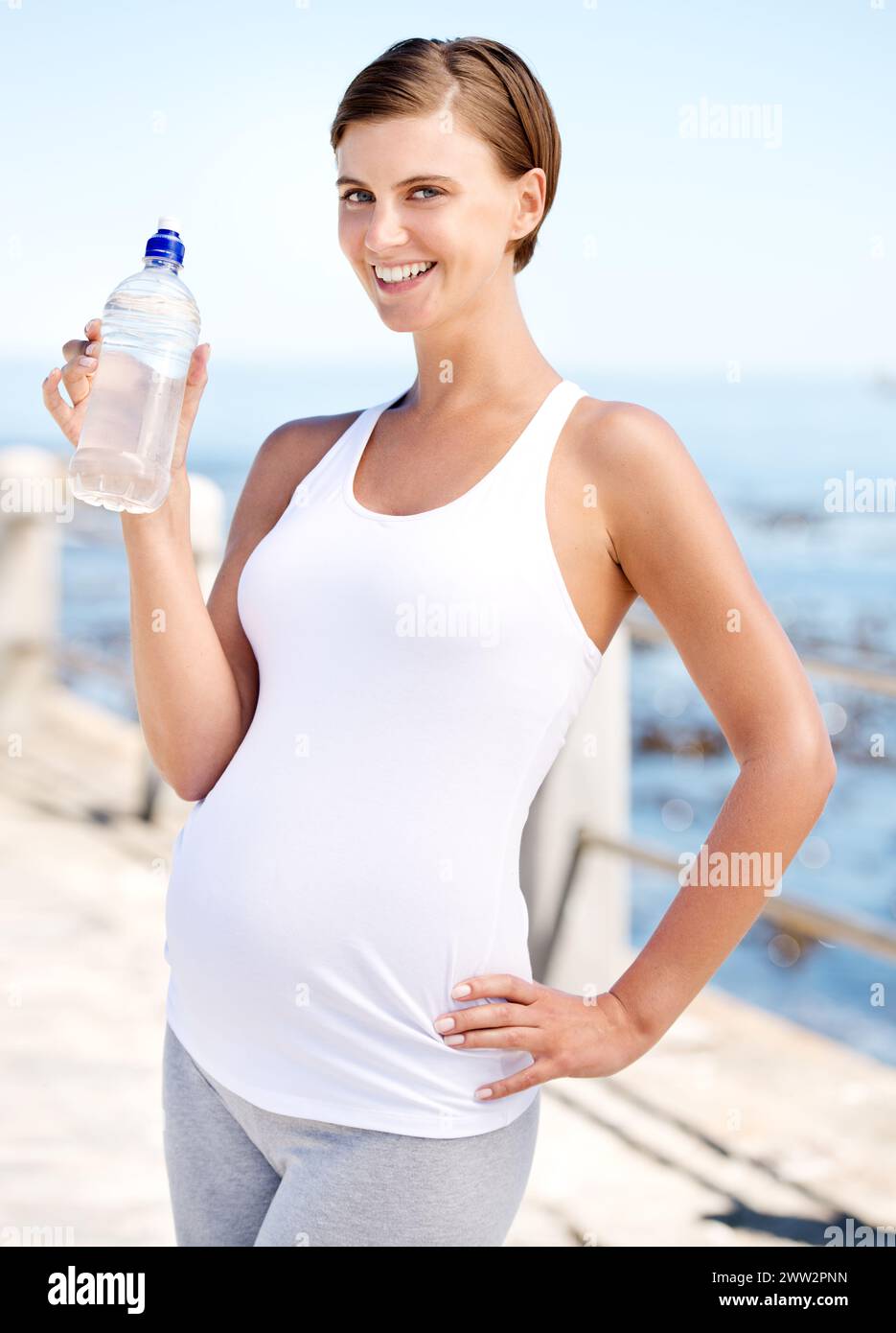Donna incinta, bottiglia d'acqua e all'aperto in spiaggia con salute prenatale, fitness con h2o e oceano. Nutrizione, gravidanza e mamma assetata, idratazione Foto Stock