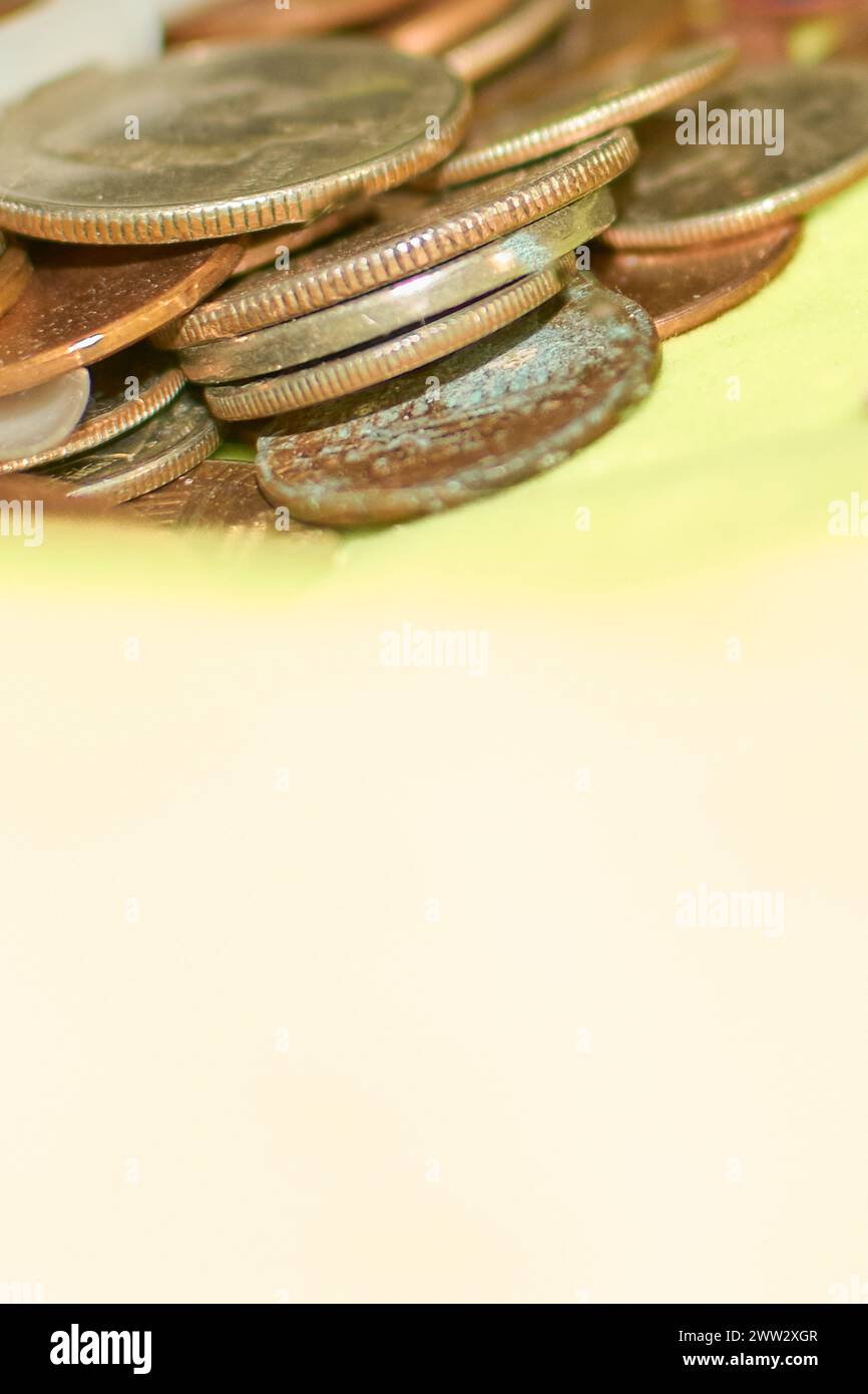 Una pila di monete vecchie e usurate è impilata su una superficie gialla brillante, che mostra i dettagli della consistenza e del colore arrugginito. Foto Stock