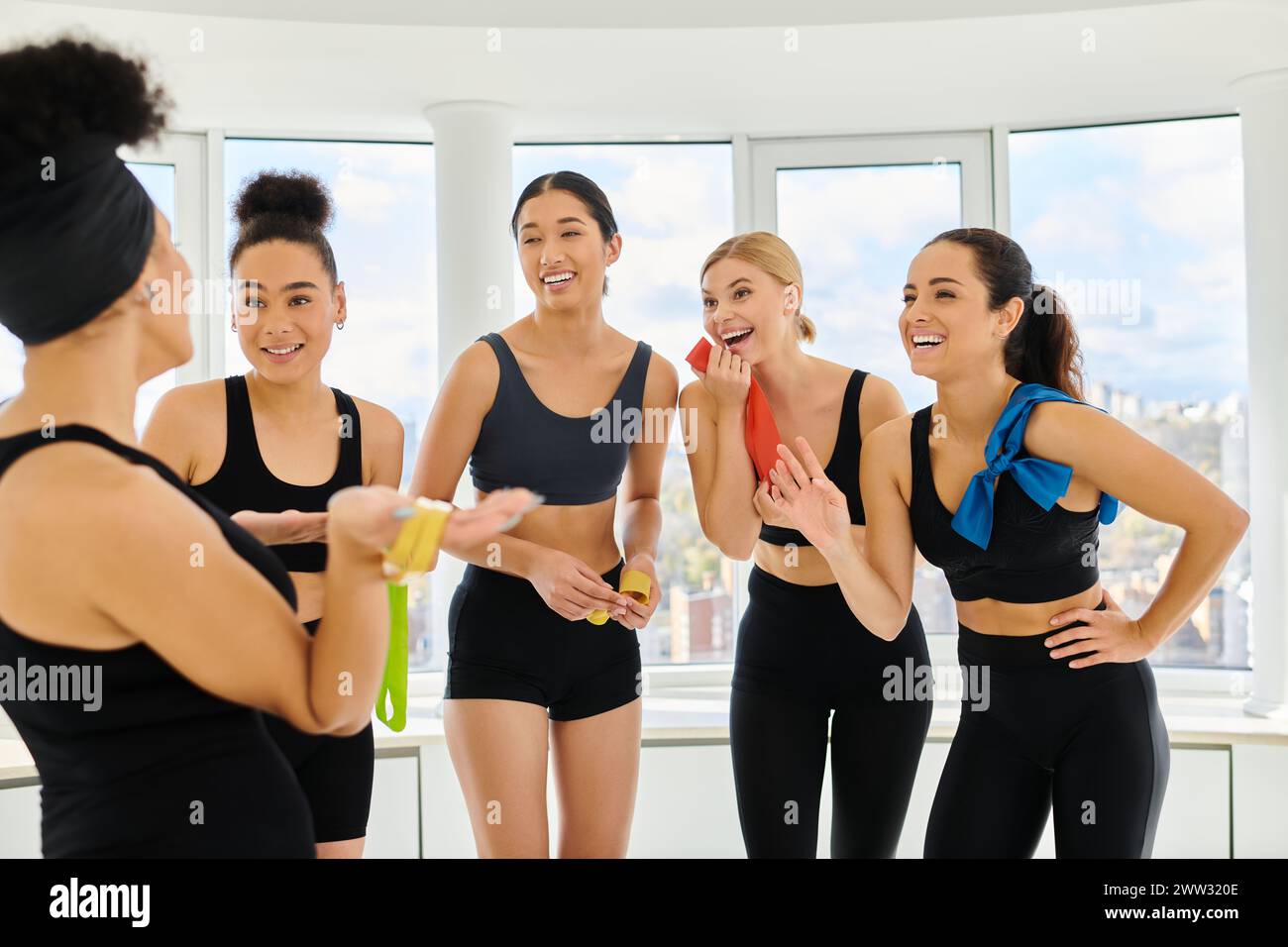 un gruppo di diverse sportivi felici che tengono bande di resistenza e ridono dopo l'allenamento Foto Stock