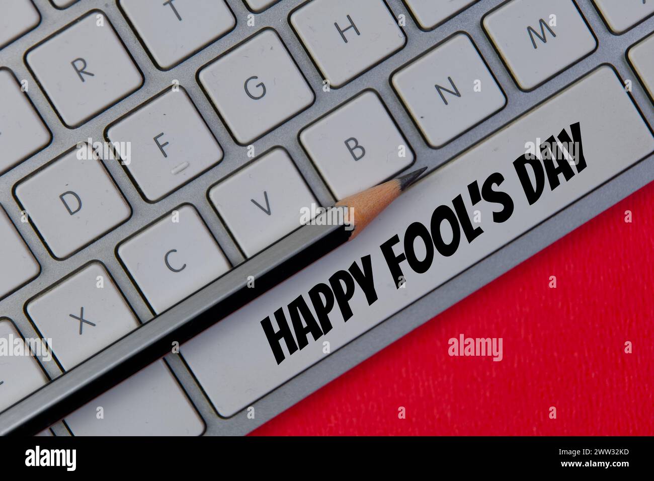 Una divertente foto ravvicinata di una tastiera bianca e nitida con il messaggio "Happy April Fool's Day" digitato sapientemente sul tasto della barra spaziatrice Foto Stock