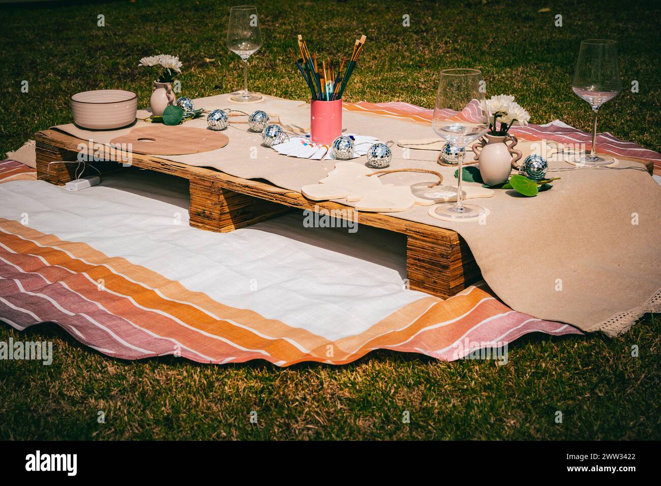 Un invitante ambiente per picnic all'aperto con forniture artistiche su una tavolozza di legno rustico. Foto Stock