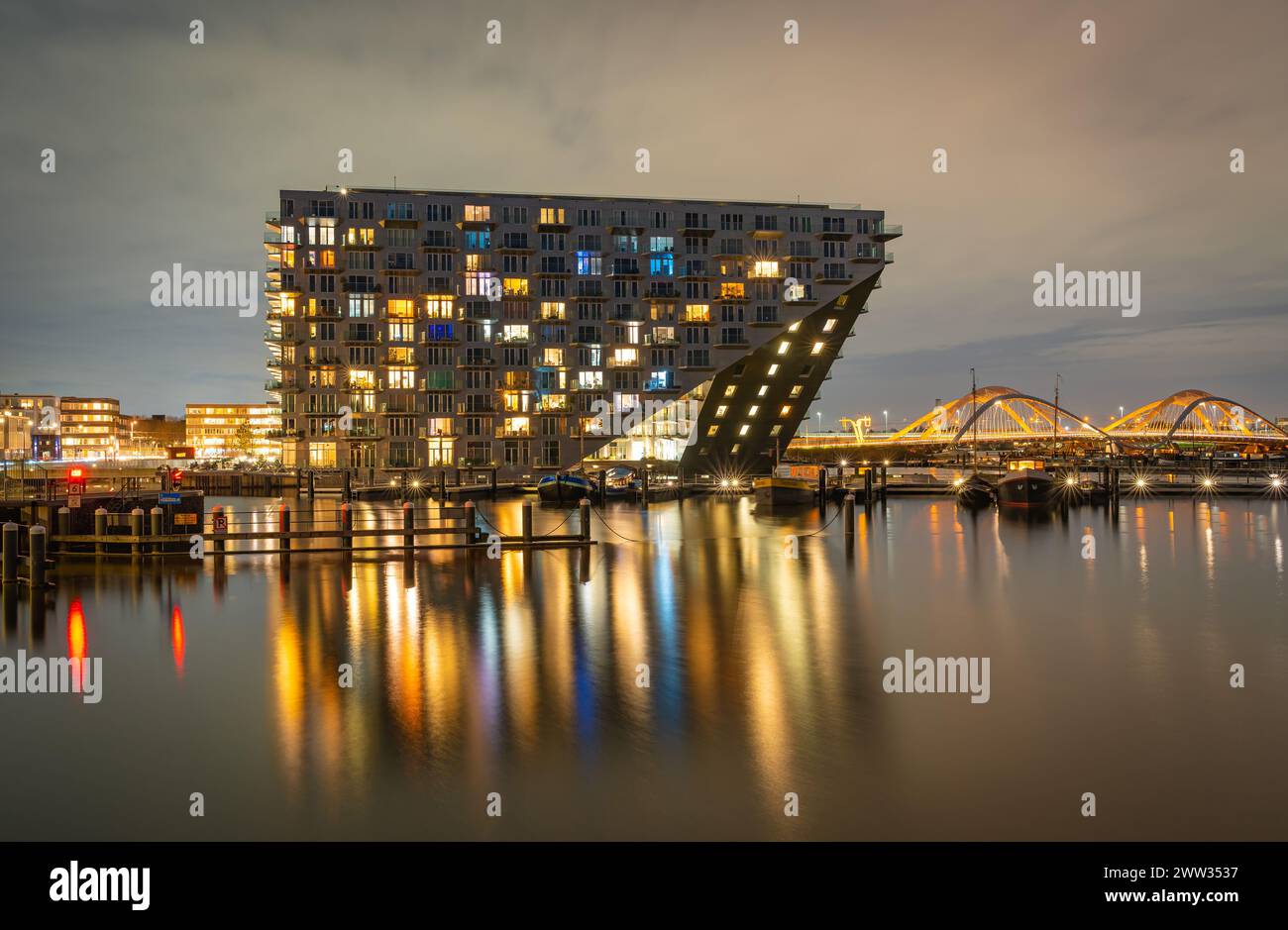 Amsterdam, Paesi Bassi, 19.03.2024, iconico edificio di appartamenti, Sluishuis e Ponte Enneüs Heerma nel quartiere di Ijburg in serata Foto Stock