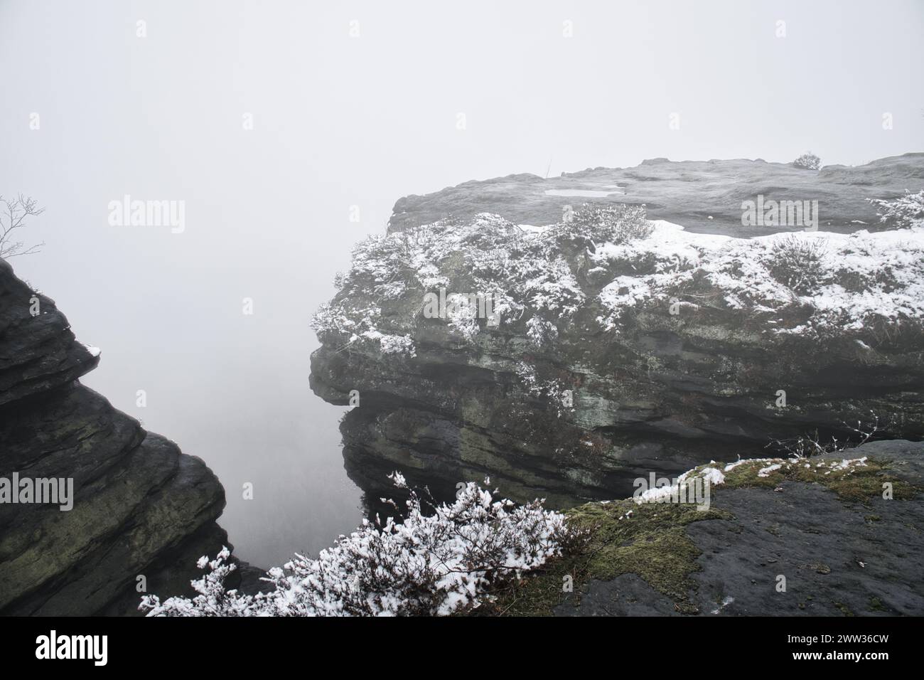 Sul grande Zschirnstein nella nebbia. Roccia ricoperta di neve. Punto panoramico durante un'escursione. Dal parco naturale delle montagne di arenaria dell'Elba. Orizzontale in Foto Stock
