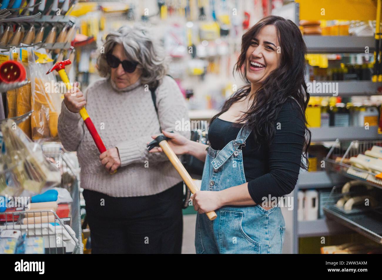 Una gioiosa interazione tra due donne con strumenti in un negozio di ferramenta Foto Stock