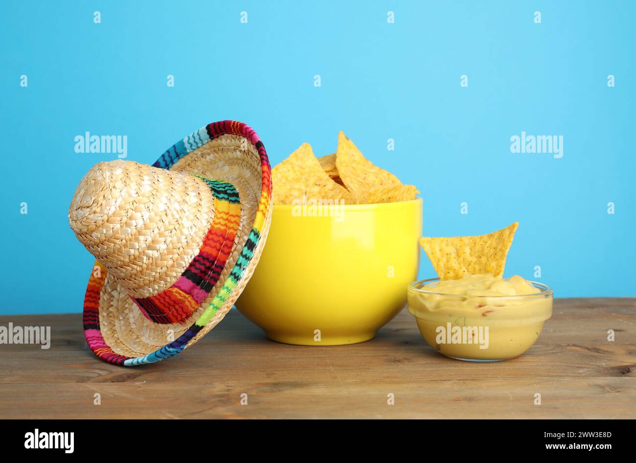 Cappello sombrero messicano, patatine di nachos e guacamole su un tavolo di legno su sfondo azzurro Foto Stock