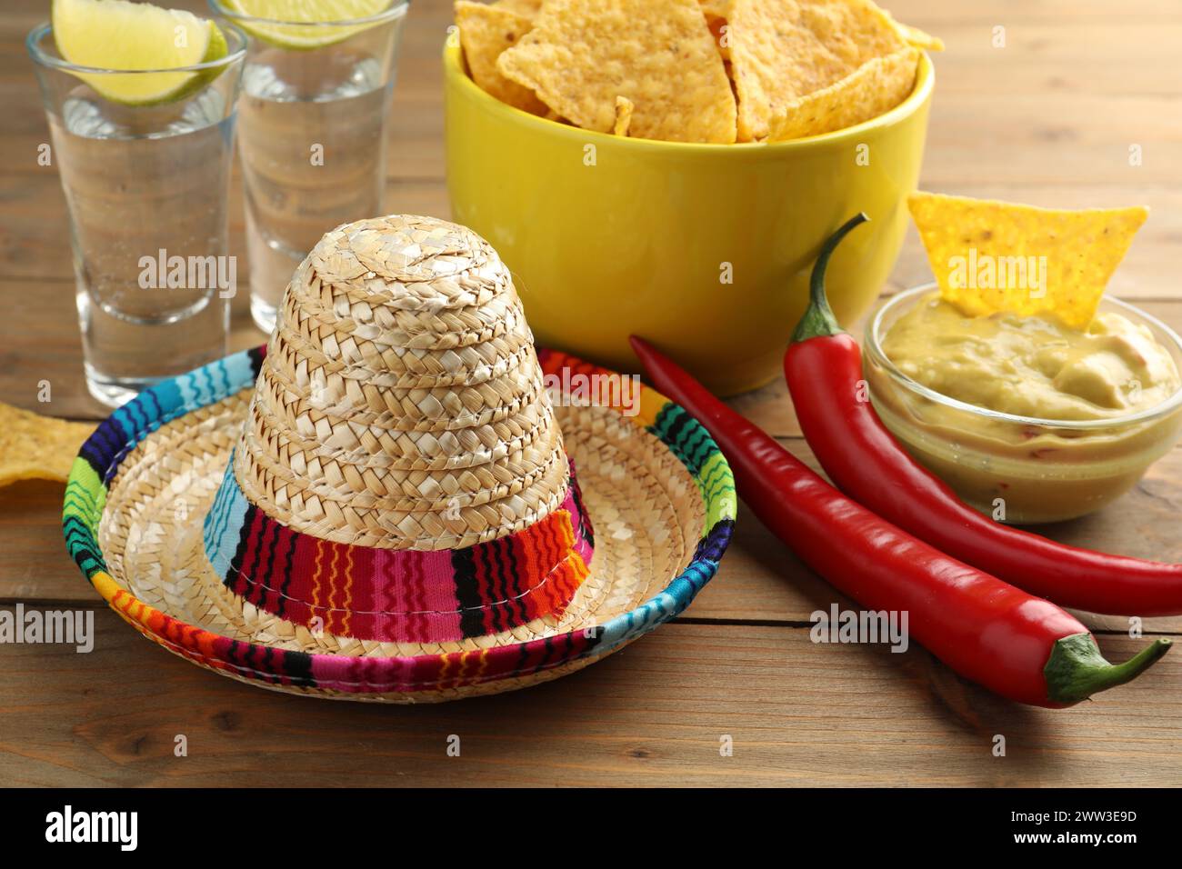 Cappello messicano sombrero, tequila, peperoncino, patatine nachos e guacamole su tavola di legno Foto Stock