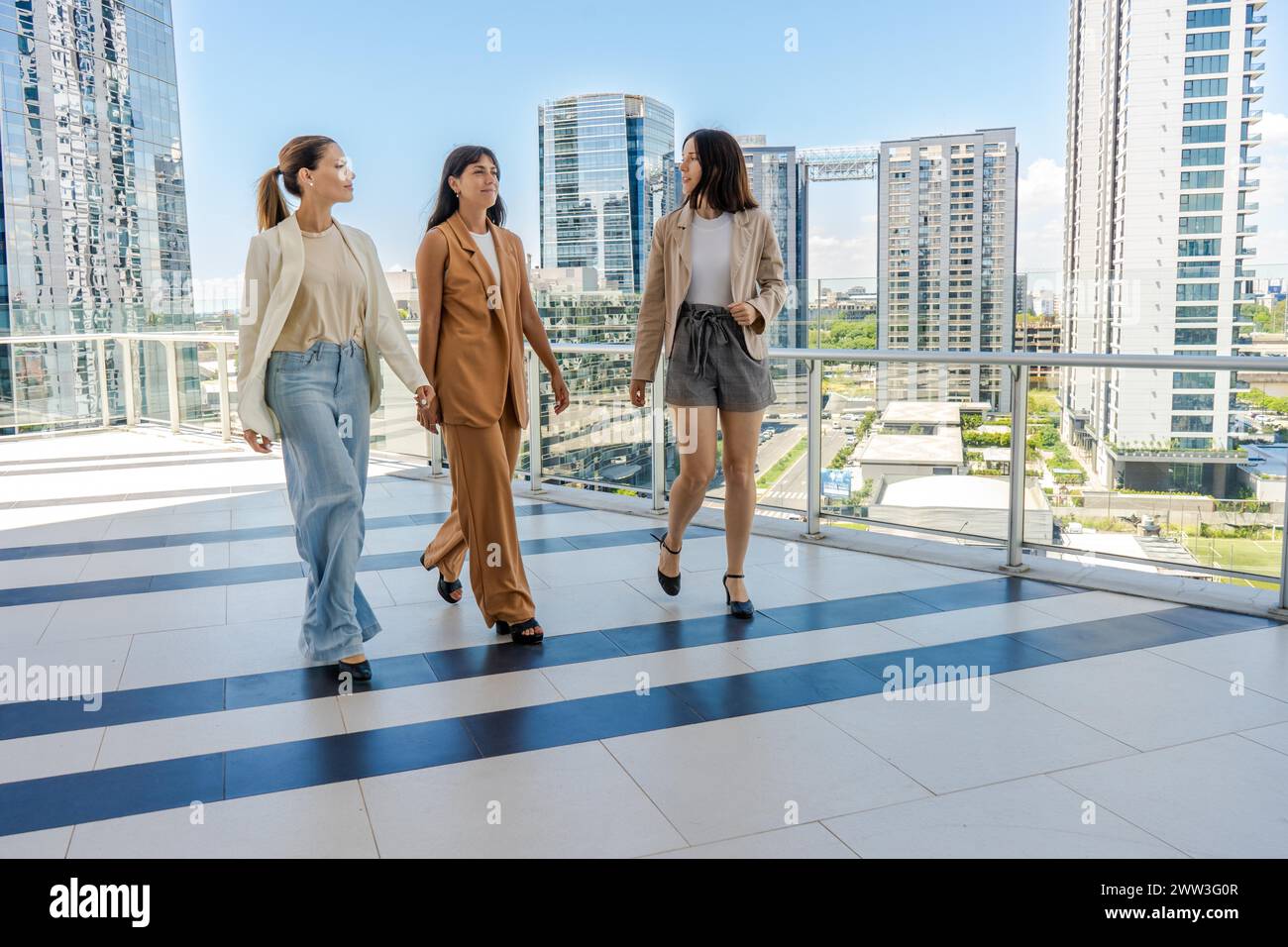 Tre donne d'affari camminano sulla terrazza di un edificio a torre Foto Stock