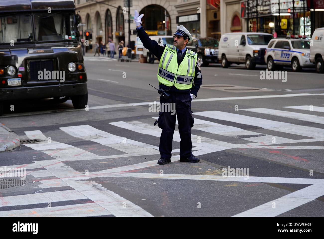 Un agente di polizia con un gilet fluorescente dirige il traffico su una strada con segnali a mano, Manhattan, New York City, New York, USA, nord America Foto Stock