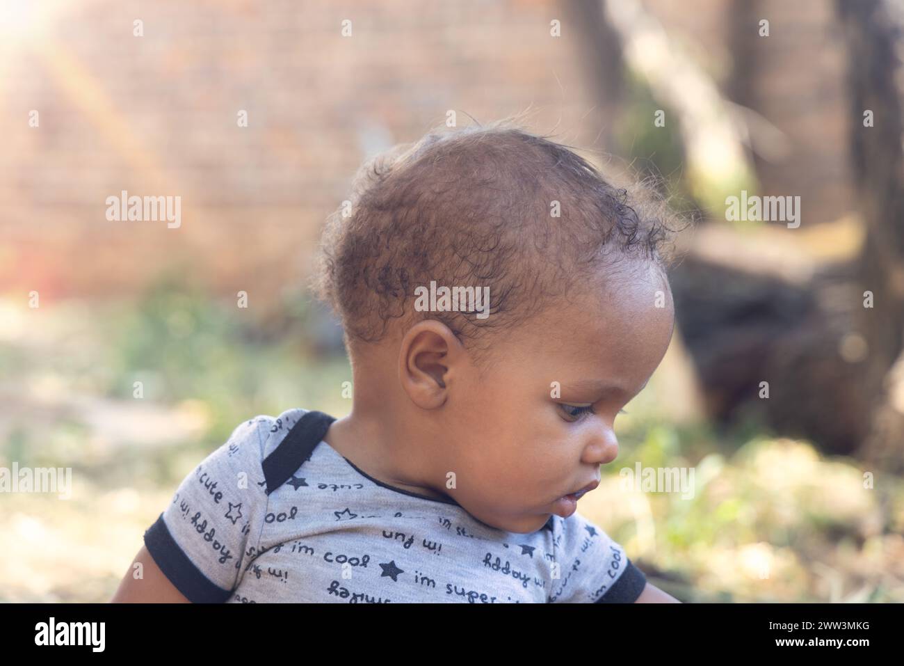 bambino africano che gioca di fronte alla casa nel tardo pomeriggio, giorno di sole Foto Stock