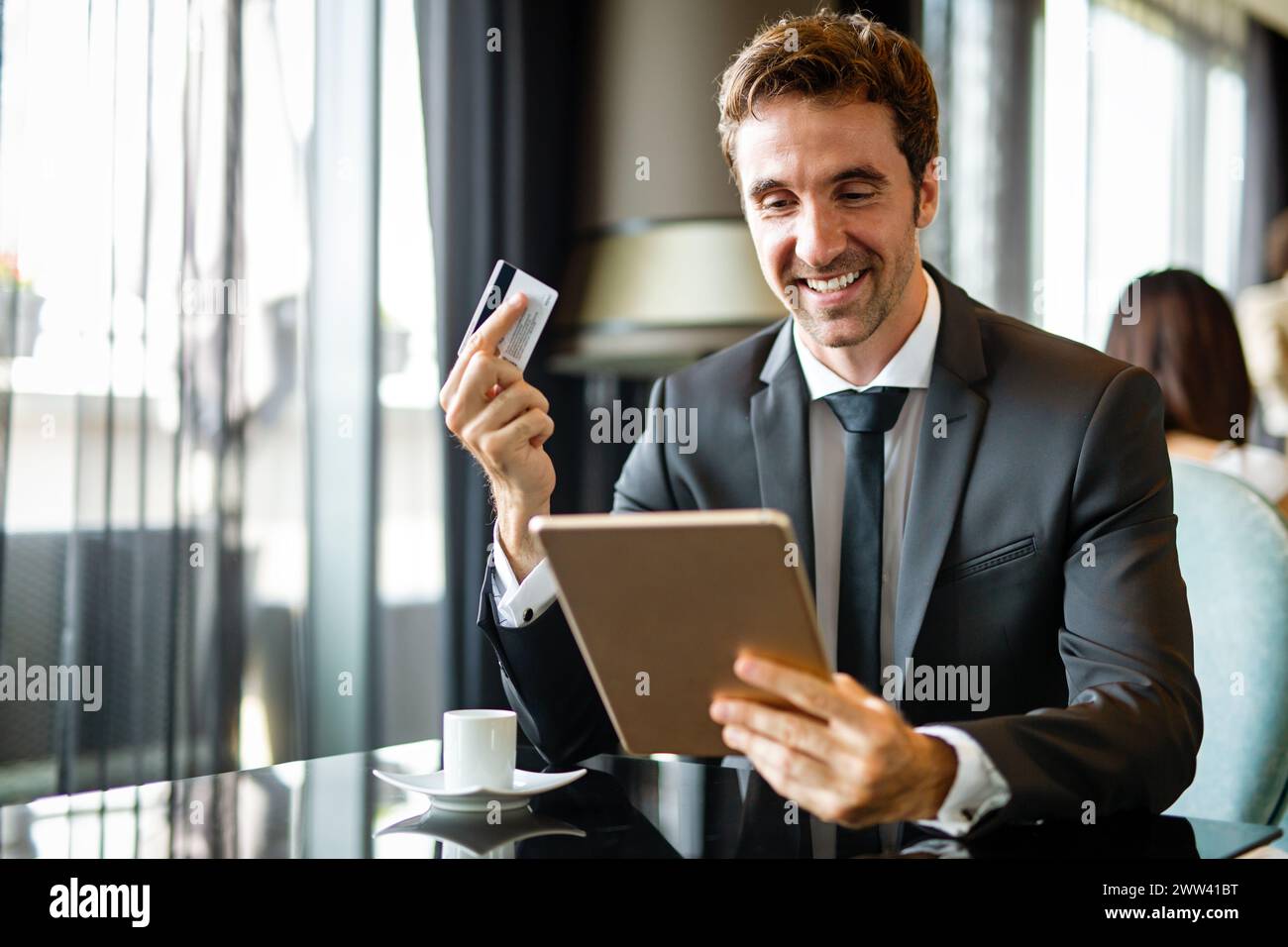 Uomo d'affari di successo che possiede una carta di credito, usando un tablet digitale. Concetto di shopping online Foto Stock
