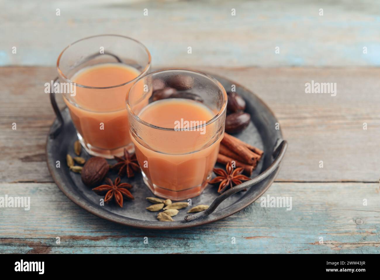 Bevanda indiana tradizionale - tè masala con spezie su vassoio di metallo su sfondo di legno Foto Stock