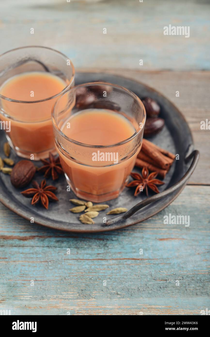 Bevanda indiana tradizionale - tè masala con spezie su vassoio di metallo su sfondo di legno Foto Stock