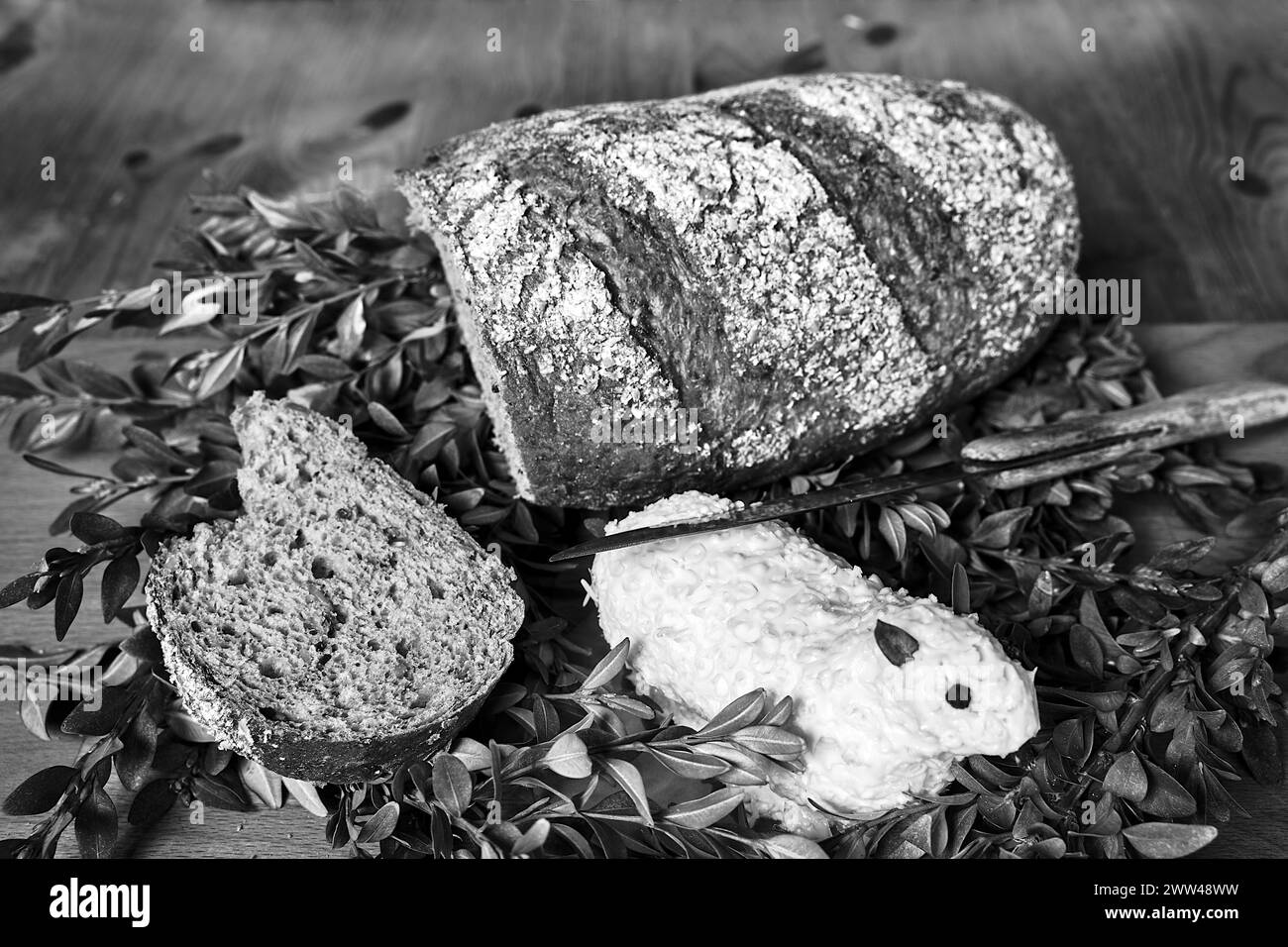 Pagnotta di pane, coltello e agnello pasquale fatto di burro su un tavolo di legno in Polonia, monocromatico Foto Stock