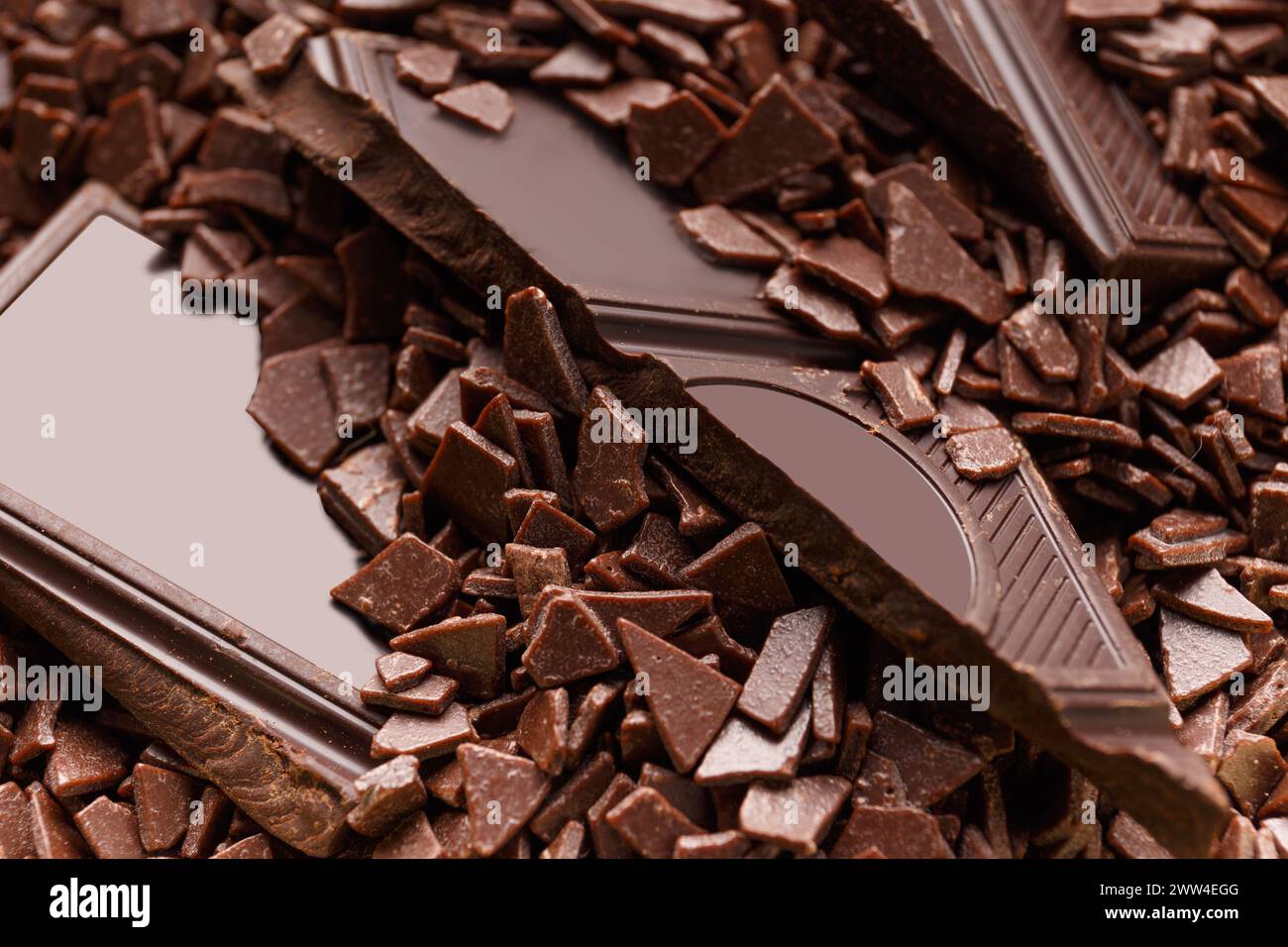 Pezzi di cioccolato fondente rotto in gocce di cioccolato primo piano. Sfondo cioccolato. Foto Stock