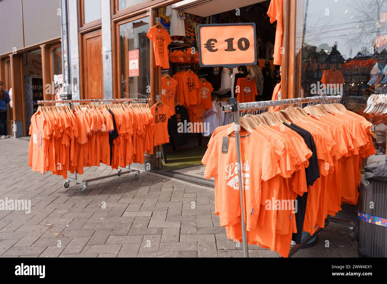 Rack di t-shirt arancioni in vendita durante il King's Day, le camicie celebrano il King's Day, esposte di fronte a un negozio - Paesi Bassi, Amsterdam, 27.04. Foto Stock