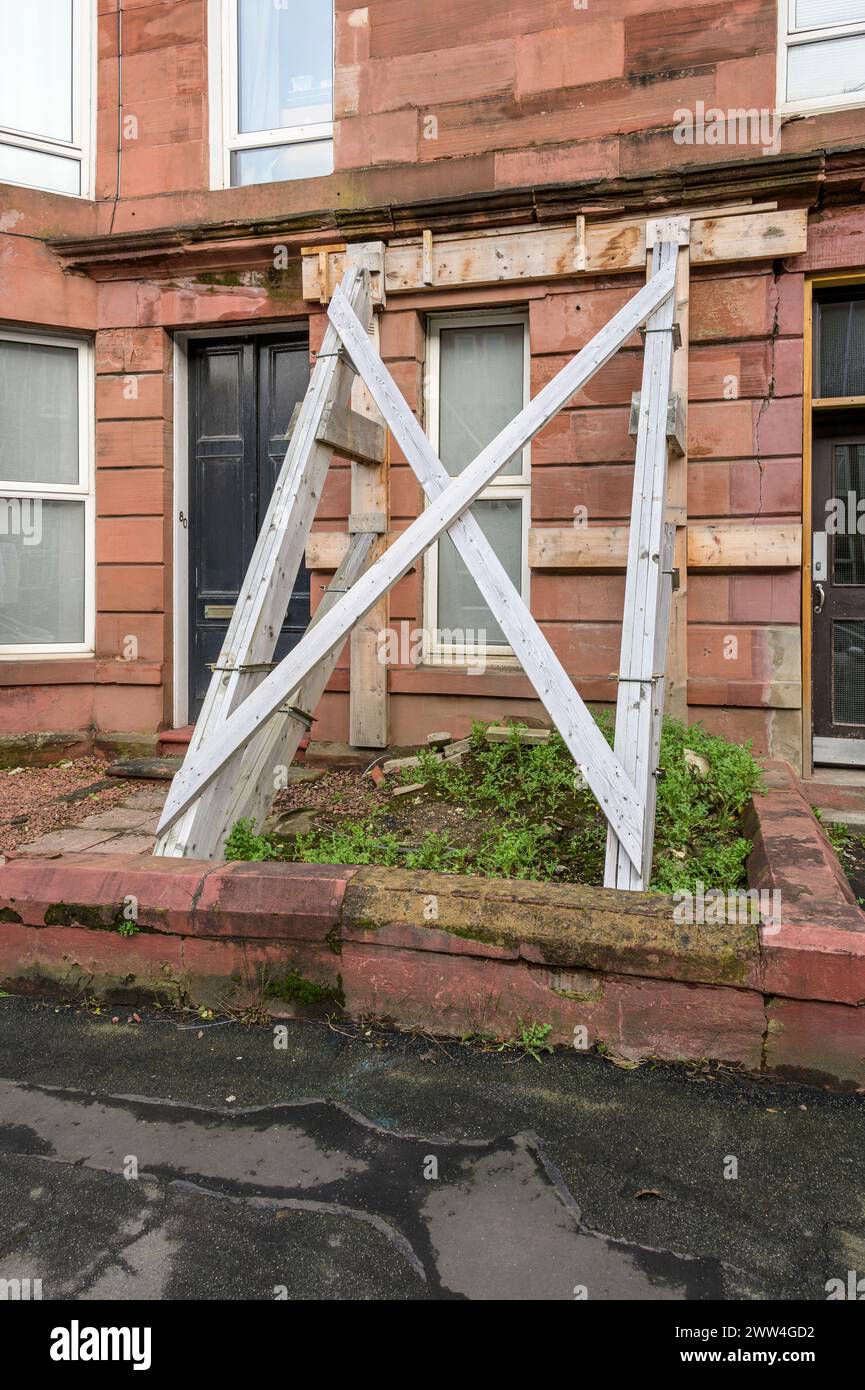 Un blocco di case popolari danneggiato sostenuto al piano terra da una punteria strutturale esterna in legno, Minard Road, Shawlands, Glasgow, Scozia, Regno Unito, Europa Foto Stock