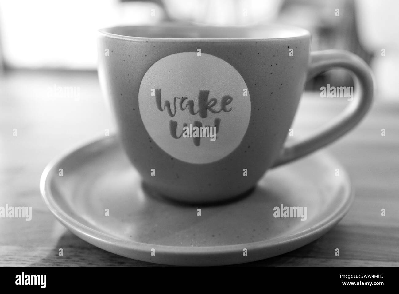 Svegliati, messaggio del nuovo giorno. Firmi lettere. Primo piano sulla tazza di caffè. Sfondo sfocato. Bianco e nero, monocromatico. Foto Stock