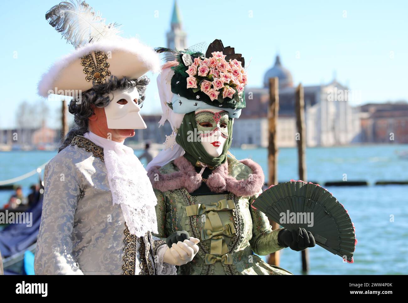 Venezia, VE, Italia - 13 febbraio 2024: Coppia con maschera veneziana al Carnevale di Venezia e mare adriatico sullo sfondo Foto Stock