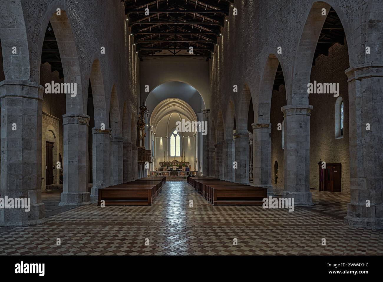 La navata principale della Basilica di Santa Maria di Collemaggio con il pavimento a scacchi e i pilastri ottagonali che sostengono gli archi. L'Aquila, Italia Foto Stock