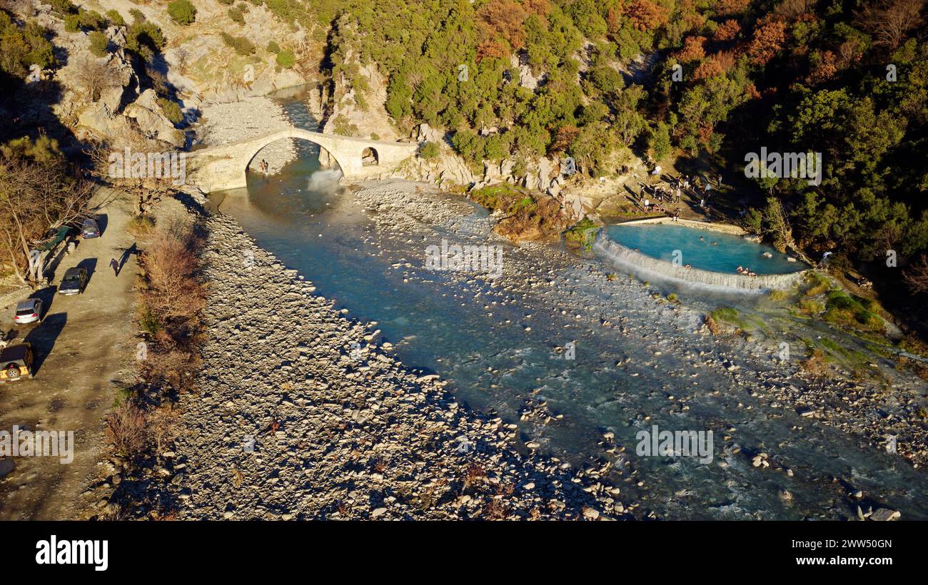 Vista aerea con droni delle persone che nuotano e fanno il bagno nelle terme termali. Ponte di Kadiut, Benje, Permet, Albania. Antico ponte di pietra. Foto Stock