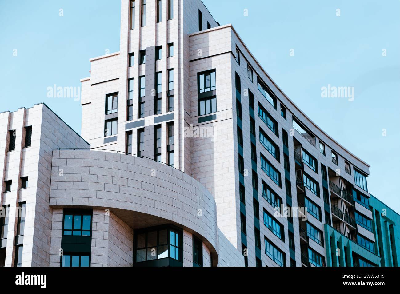 Un edificio moderno mostra i suoi elementi architettonici unici e il suo design su un cielo blu luminoso. Foto Stock