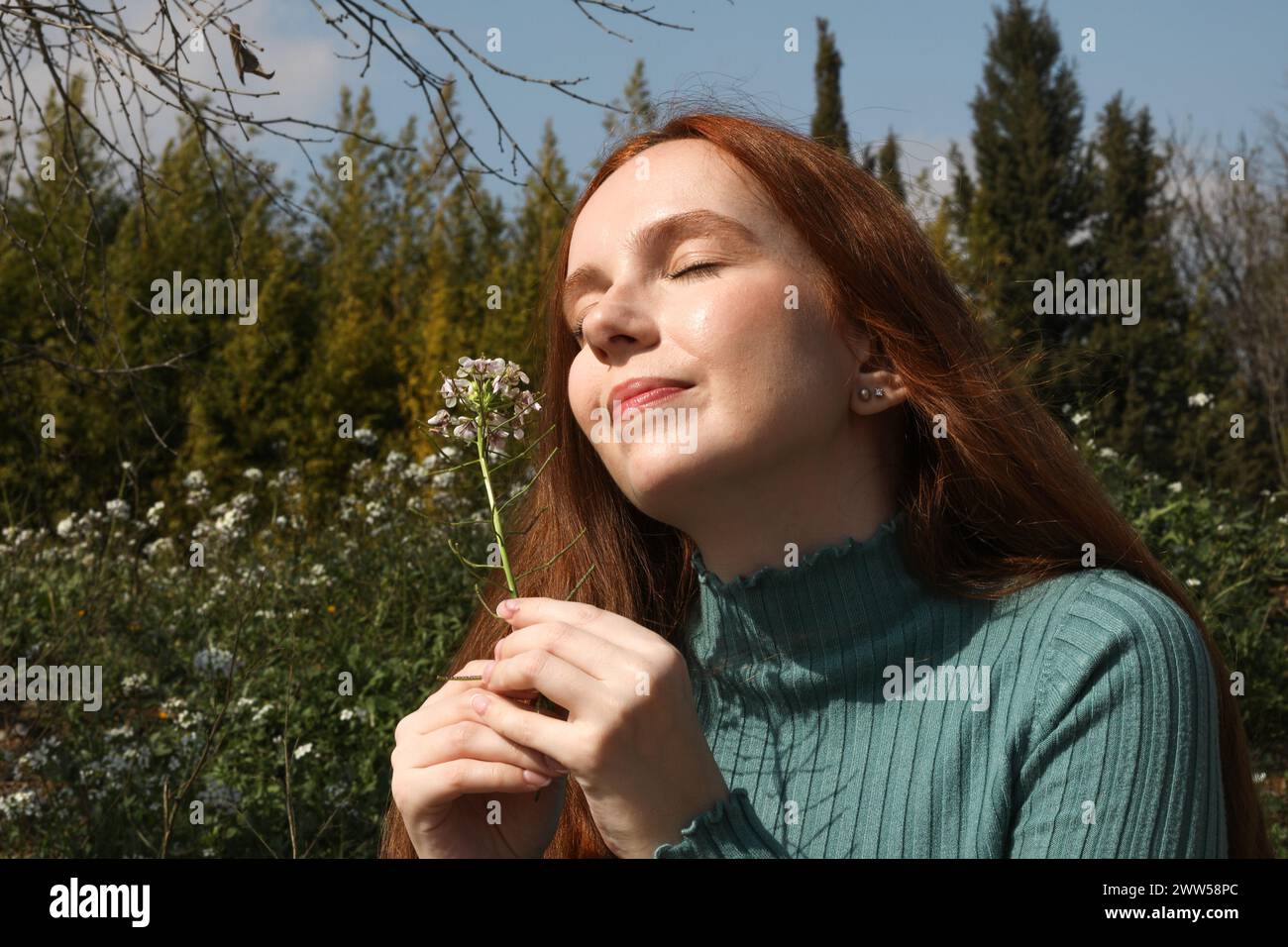Una bella donna a occhi chiusi puzza di fiore nel campo Foto Stock