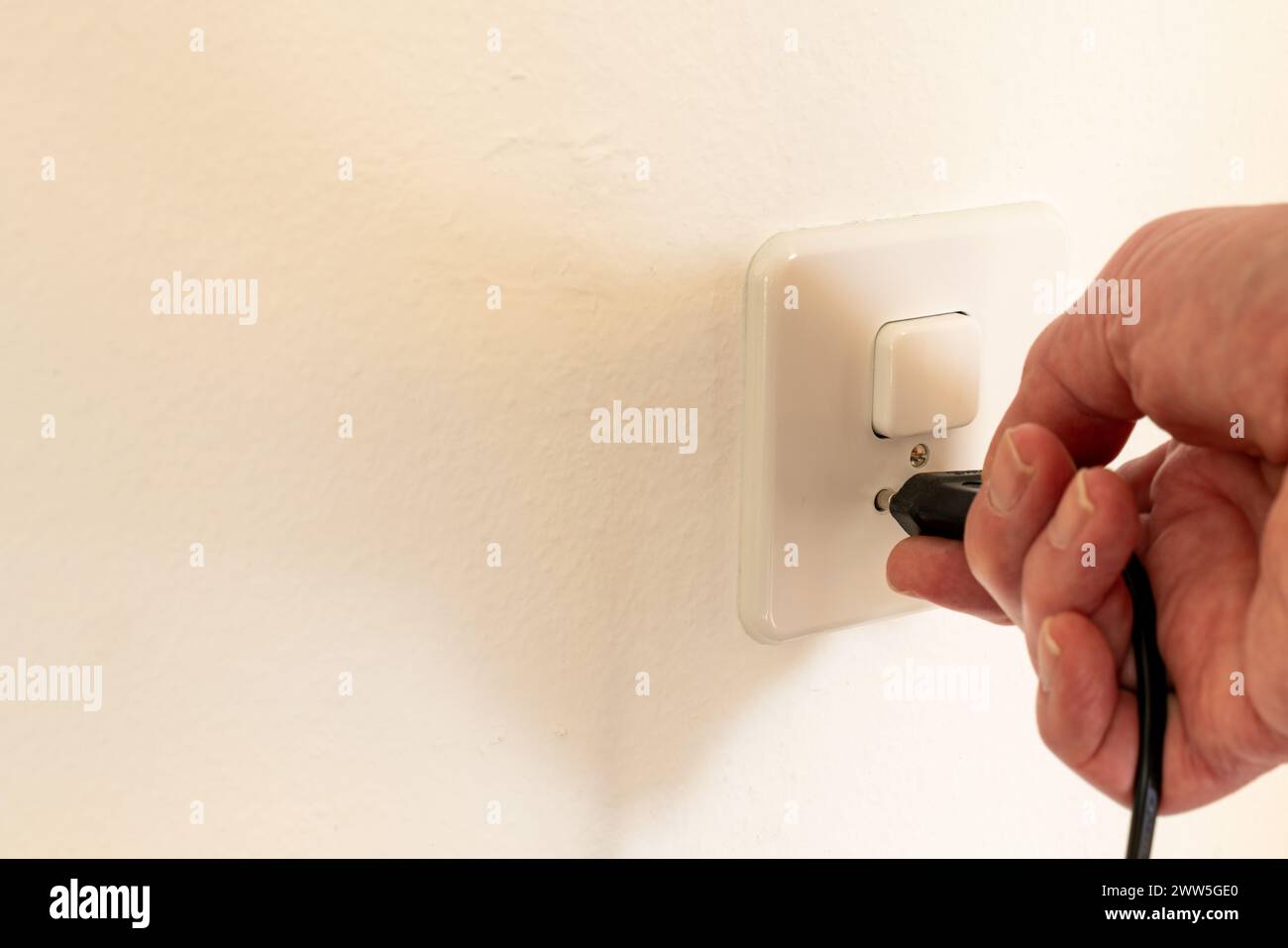Collegare una spina di alimentazione a una presa di corrente a muro. La presa di corrente è combinata con un interruttore per accendere la luce. Foto Stock