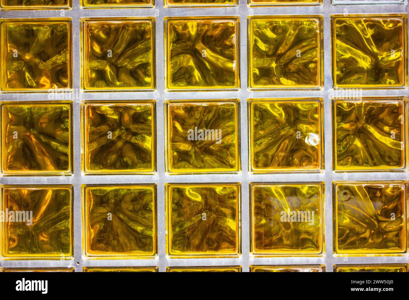 Parete in vetro trasparente giallo. Piastrelle di lusso quadrate in oro per il bagno e interni moderni. Sfondo o motivo a mosaico dorato senza cuciture. Foto Stock