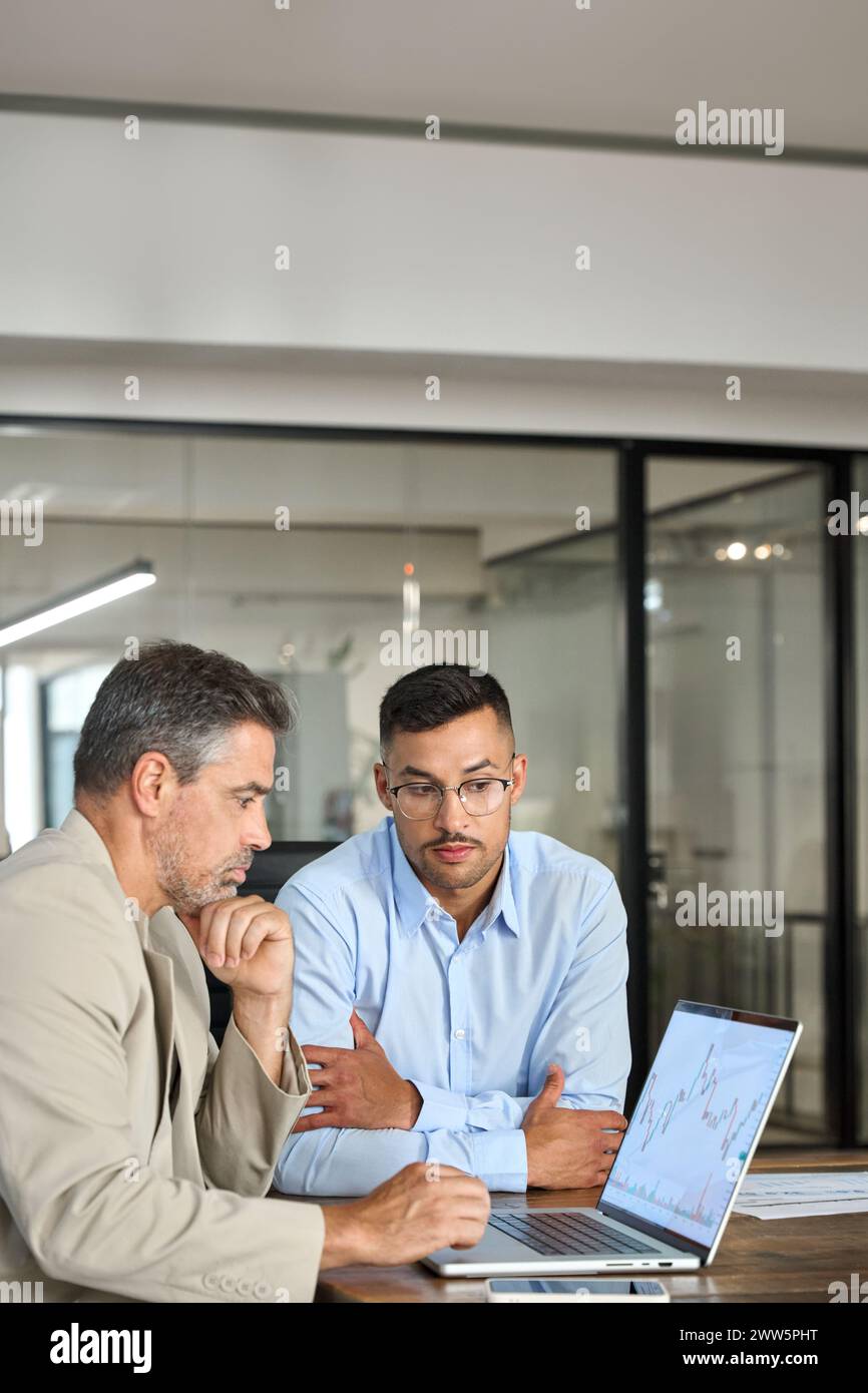 Due investitori impegnati investono nel mercato azionario finanziario utilizzando laptop. Verticale. Foto Stock