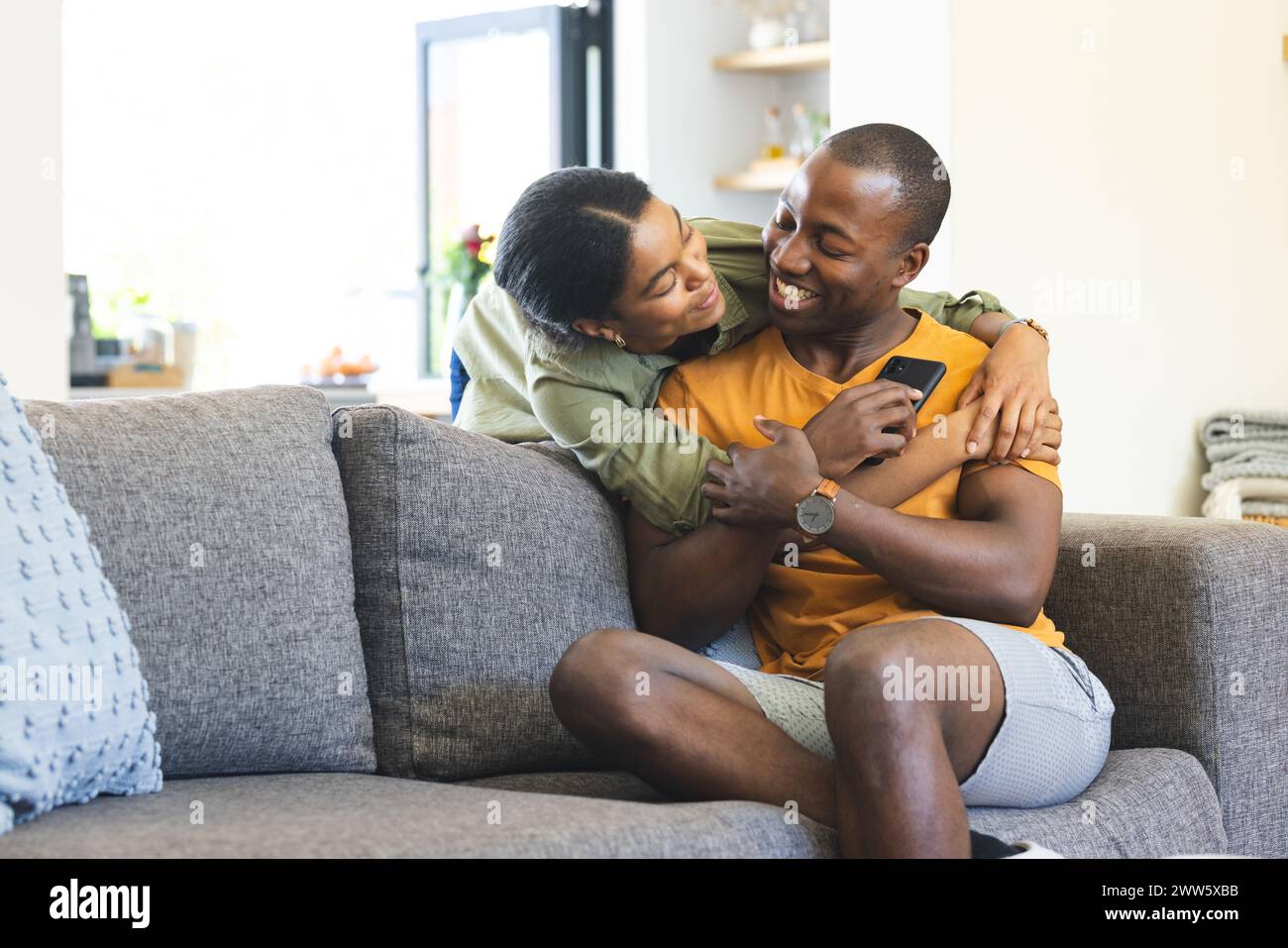 Una giovane coppia afroamericana condivide un momento accogliente sul divano di casa con spazio per copiare Foto Stock