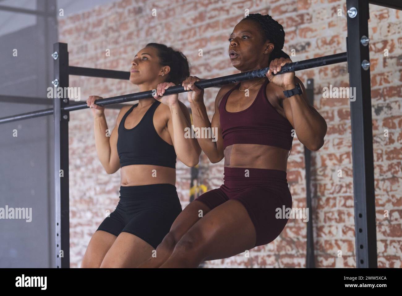 Due donne in forte forma si impegnano in un allenamento pull-up in palestra Foto Stock