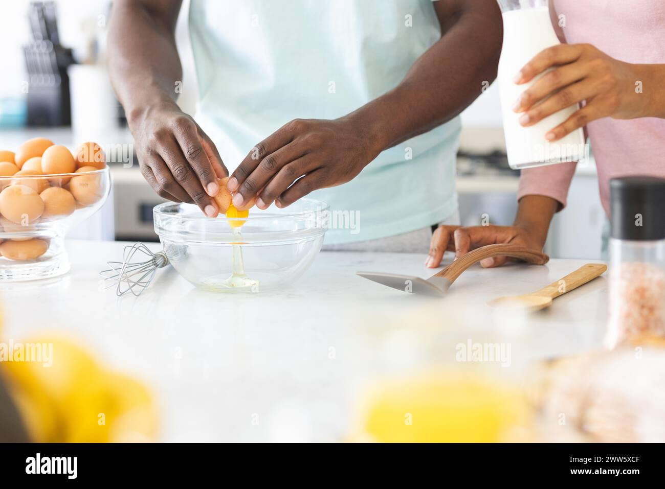 Una coppia diversificata prepara il cibo insieme in una cucina di casa, preparando uova Foto Stock
