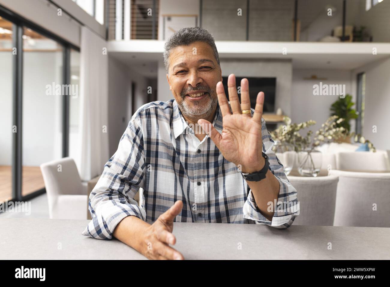Un uomo birazziale di mezza età sta sventolando alla telecamera in un video a casa Foto Stock