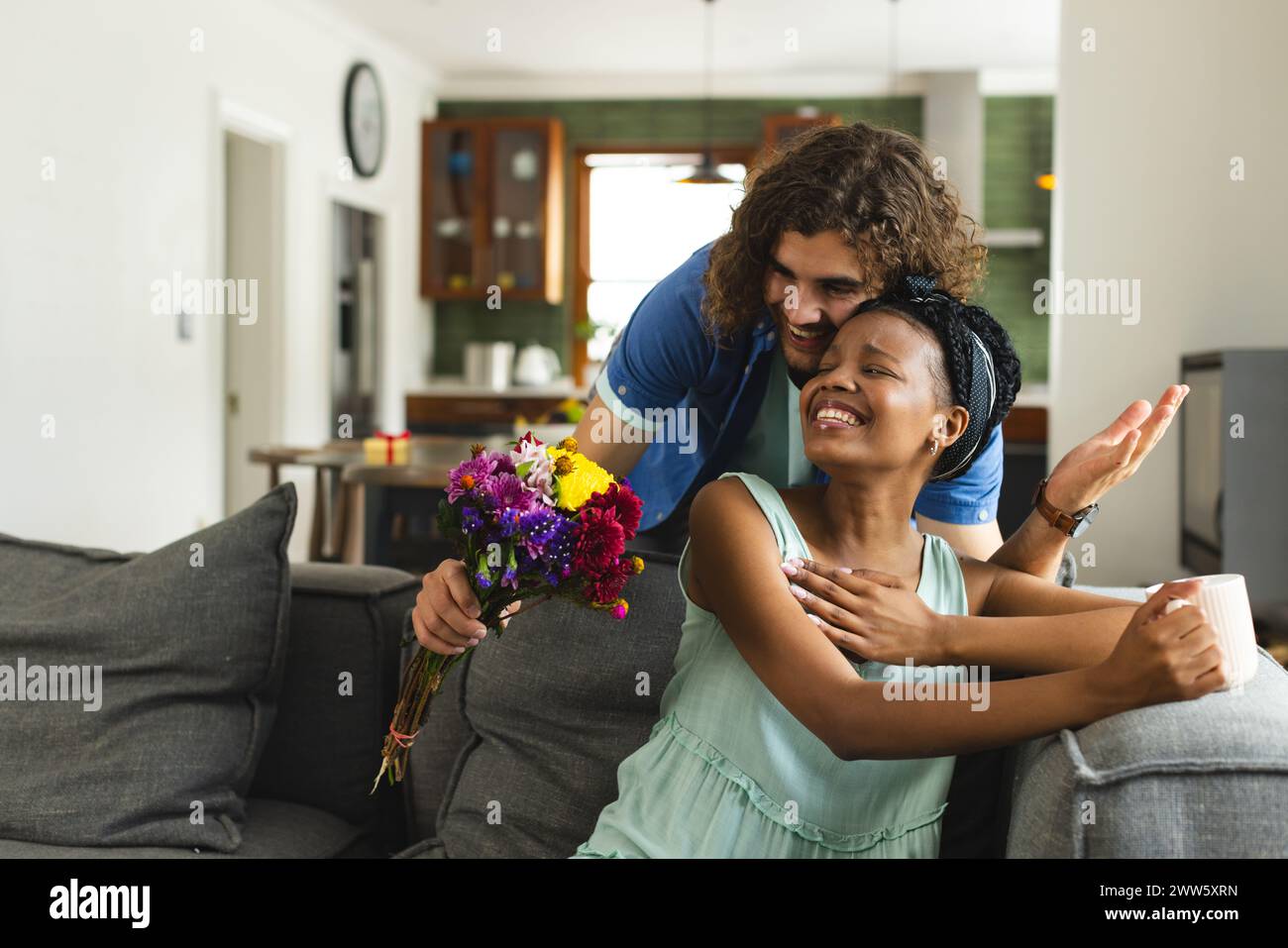 Una coppia diversa condivide un momento tenero a casa sul divano Foto Stock