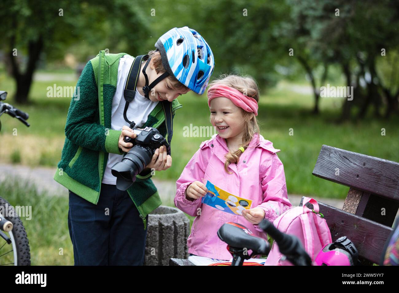 Ragazzo e ragazza che guardano la fotocamera e sorridono. Fratello che mostra una foto che ha portato alla sorella minore. Bambini che parlano e ridono Foto Stock