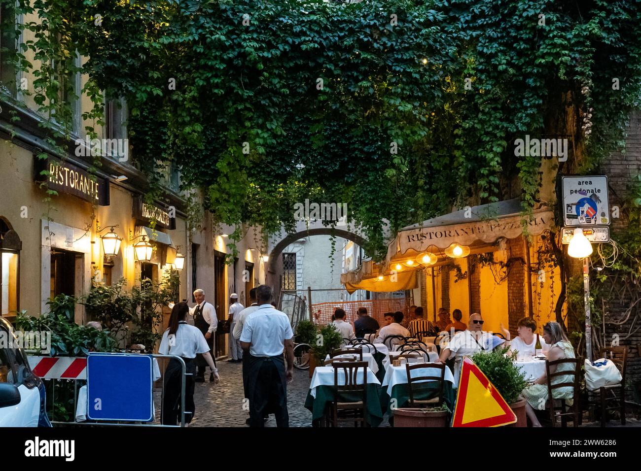 Roma, Italia - 15 agosto 2023: Ristorante con posti a sedere all'aperto di sera. I camerieri servono cibo all'aperto Foto Stock