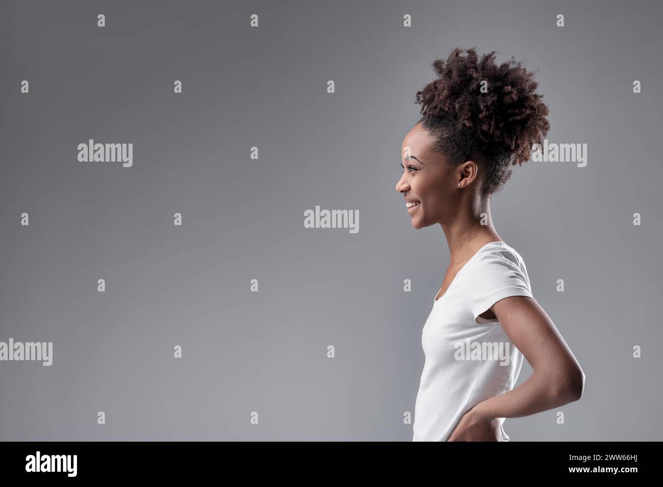 lo sguardo laterale della giovane donna trasuda fiducia, con la sua acconciatura naturale che accentua il suo carattere Foto Stock
