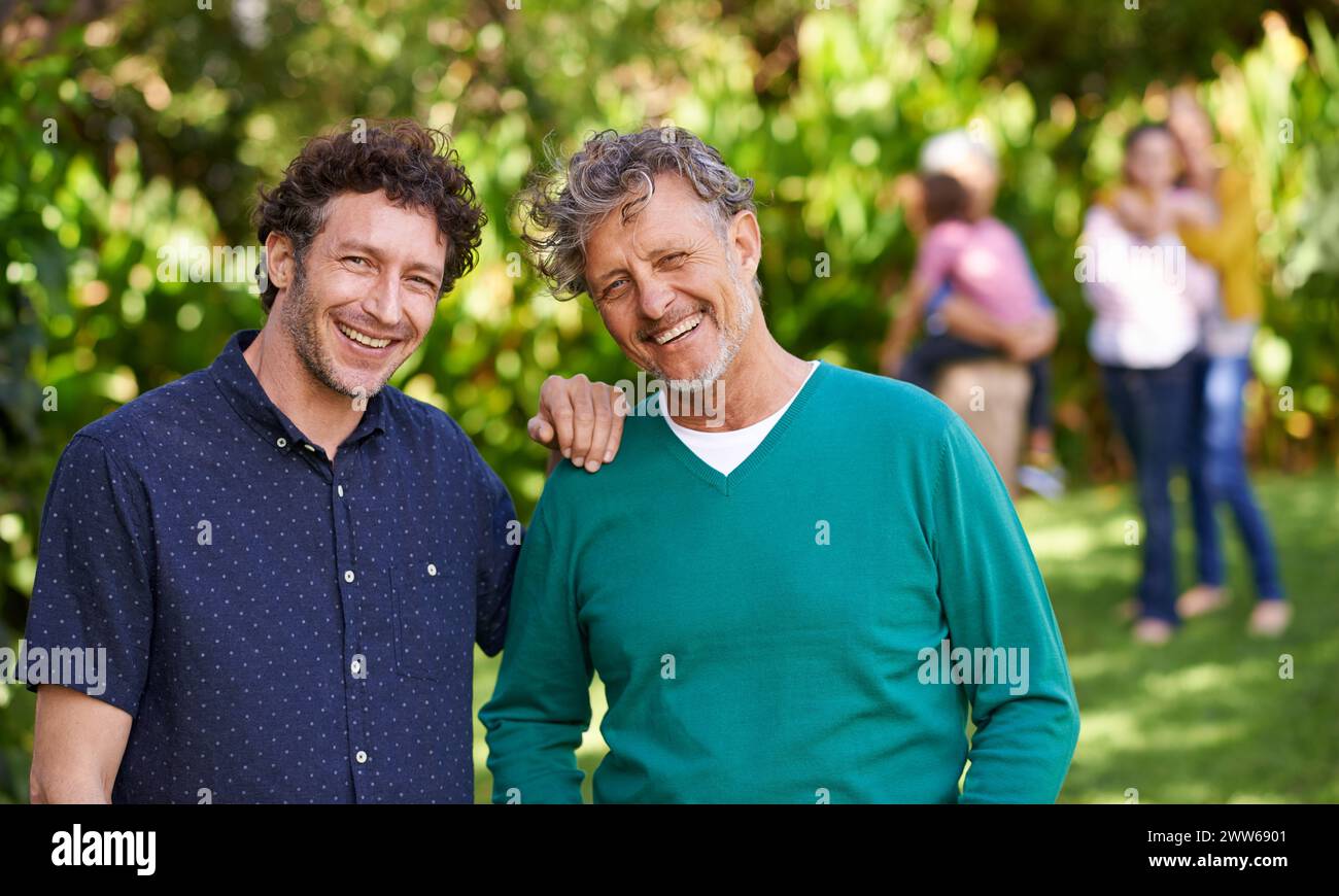 Ridi, papà e ritratti con l'uomo per legare, affetto e amore per rilassarsi in giardino, nel cortile e nella natura. Uomini, famiglia e uomini con il sorriso Foto Stock